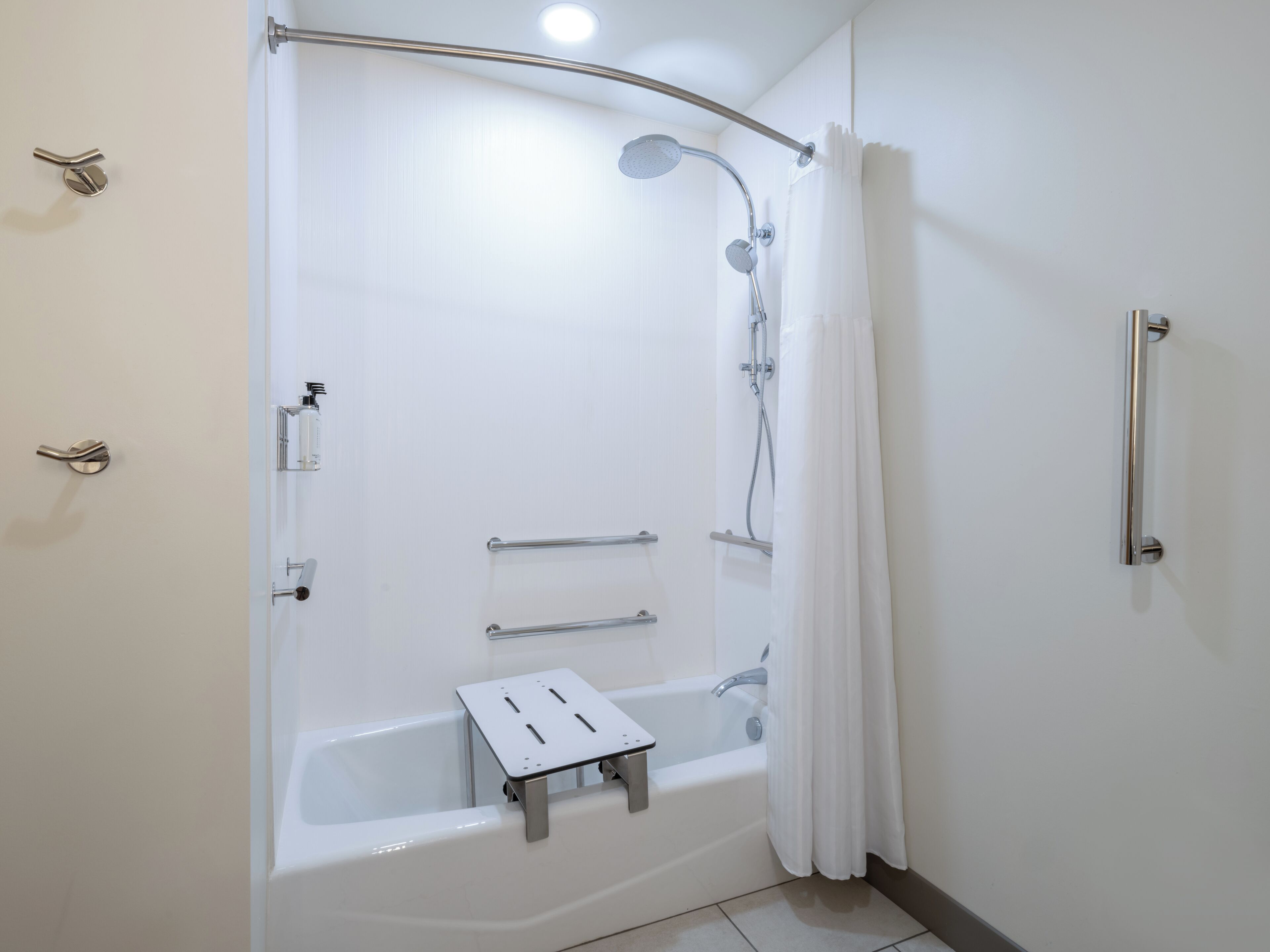 A modern bathroom with a walk-in shower, grab bars, and a handheld showerhead.
