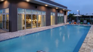 Un edificio moderno con piscina, zona de estar al aire libre y bar.