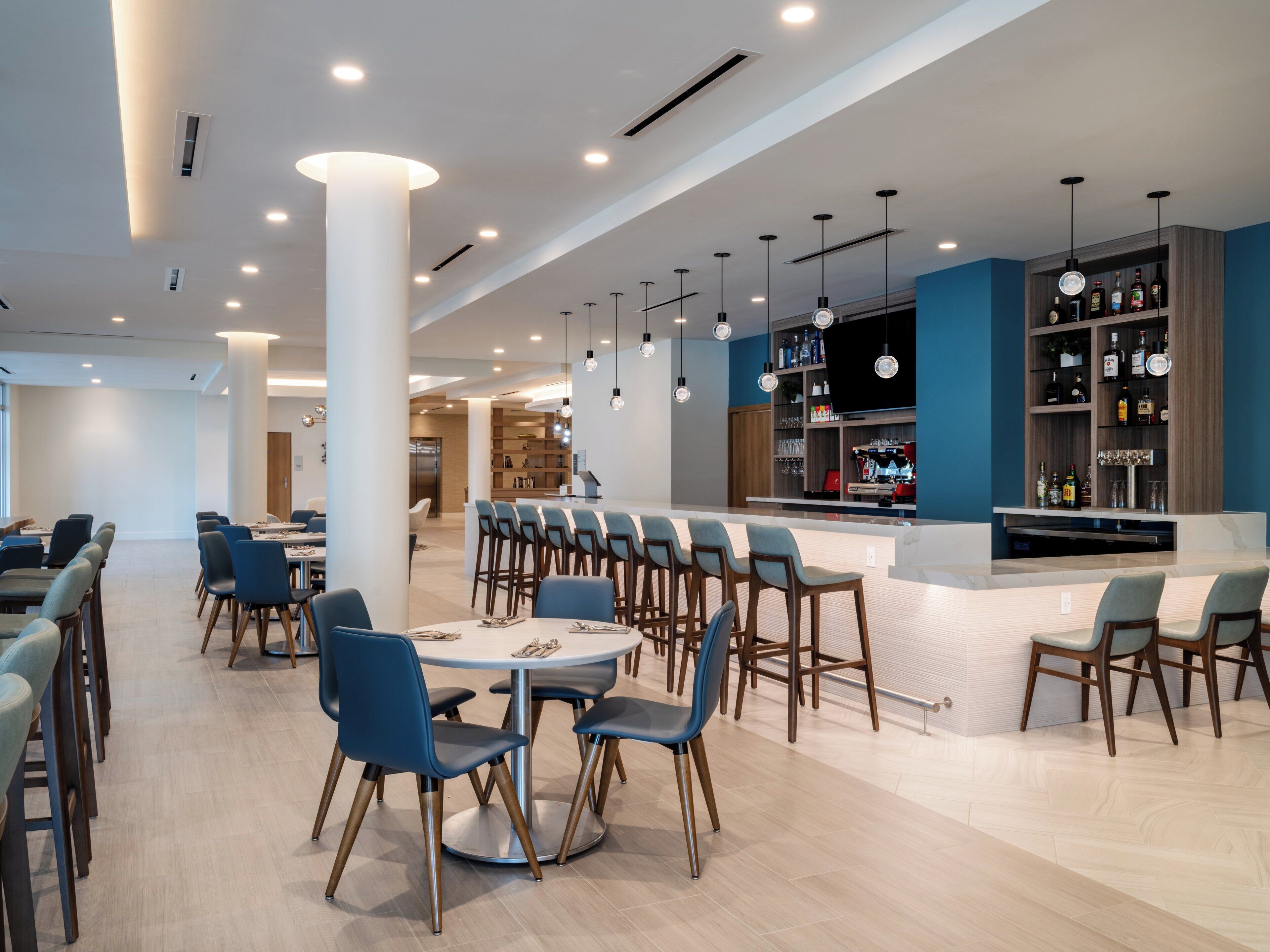 Un restaurante moderno con barra, techos altos e iluminación contemporánea.