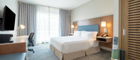 Una habitación de hotel con cama, escritorio, silla, televisor y armario de madera.