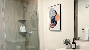 Une salle de bain moderne avec une douche à parois de verre, des toilettes, un comptoir en marbre et des meubles en bois.