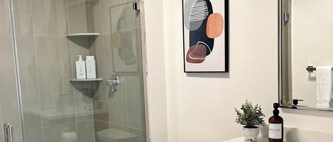 Un baño moderno con cabina de ducha de vidrio, inodoro, encimera de mármol y armarios de madera.