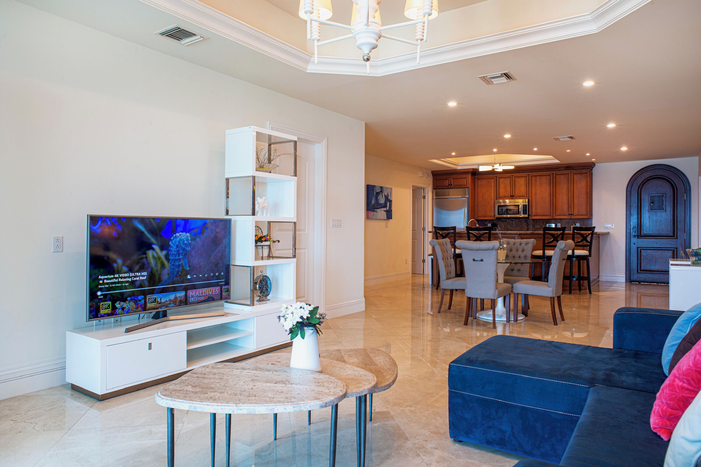 A modern living room with a flat-screen TV, a coffee table, and a blue sofa.