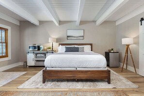 A bedroom with a wooden bed, a nightstand, a lamp, and a wall-mounted TV. - Big Pine Suite CN Lodge R#1 (Springville)
