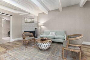 A living room with a fireplace, two armchairs, a sofa, and a patterned rug.