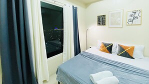 Ein Hotelzimmer mit Bett, Vorhängen, einem Fenster und Wandbildern.