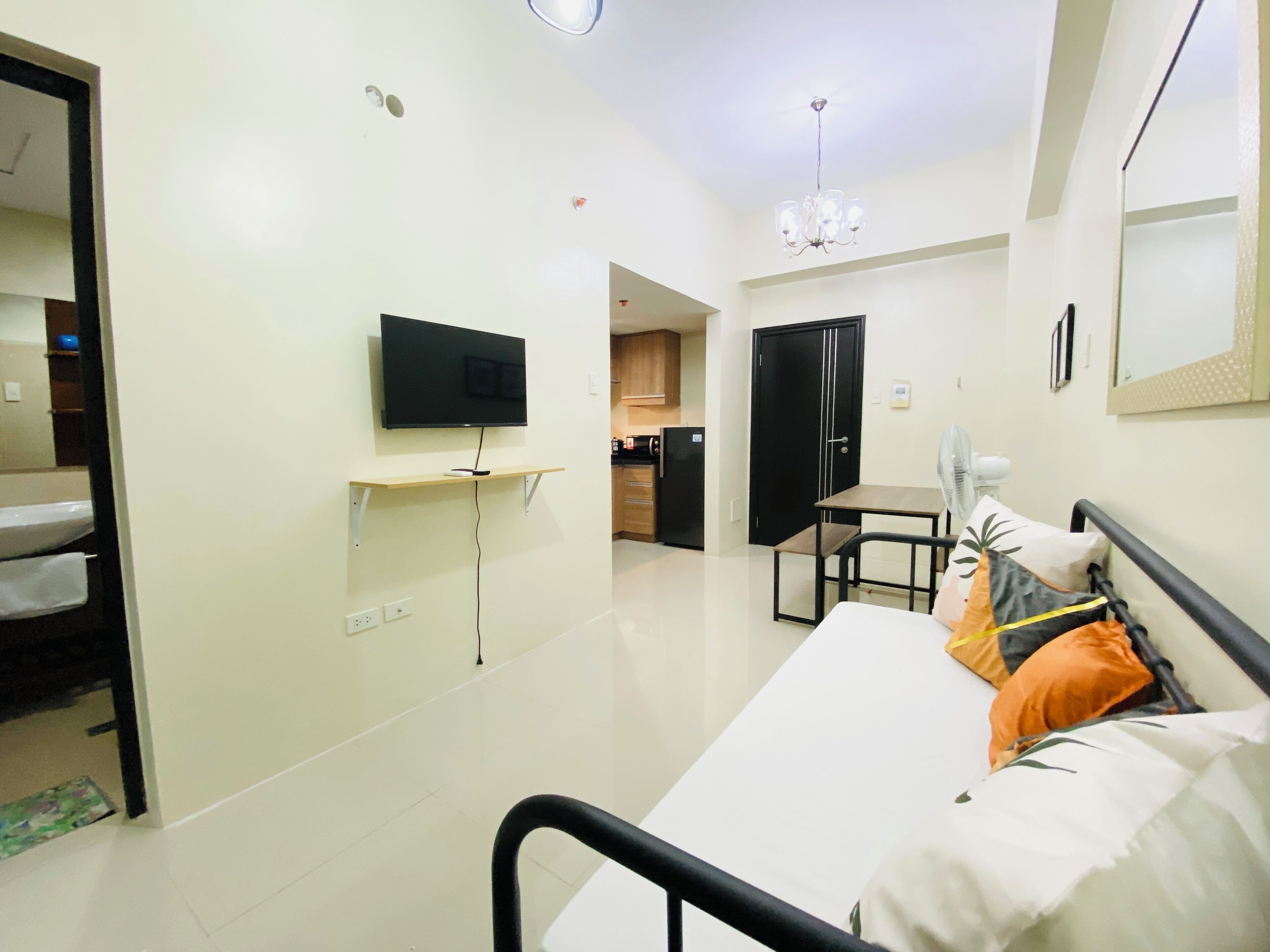 Een slaapkamer met een bed, een tv aan de muur, een klein tafeltje, een stoel en een kledingkast.