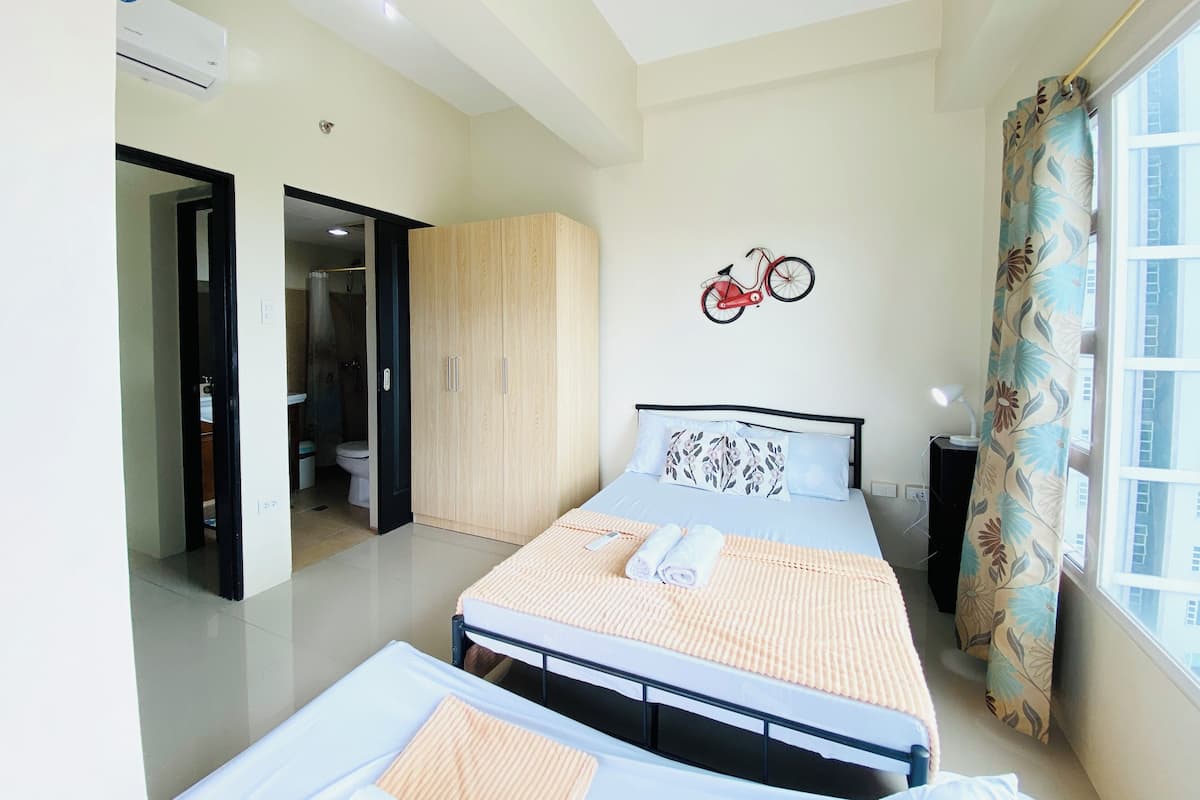 Un dormitorio moderno con cama, armario y baño visible a través de una puerta abierta.