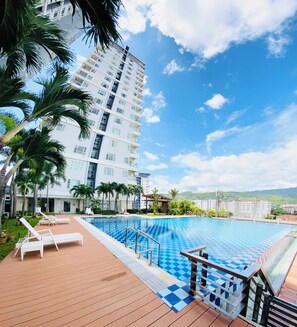 Un hotel moderno con zona de piscina, sillones de descanso y vistas de los edificios circundantes.