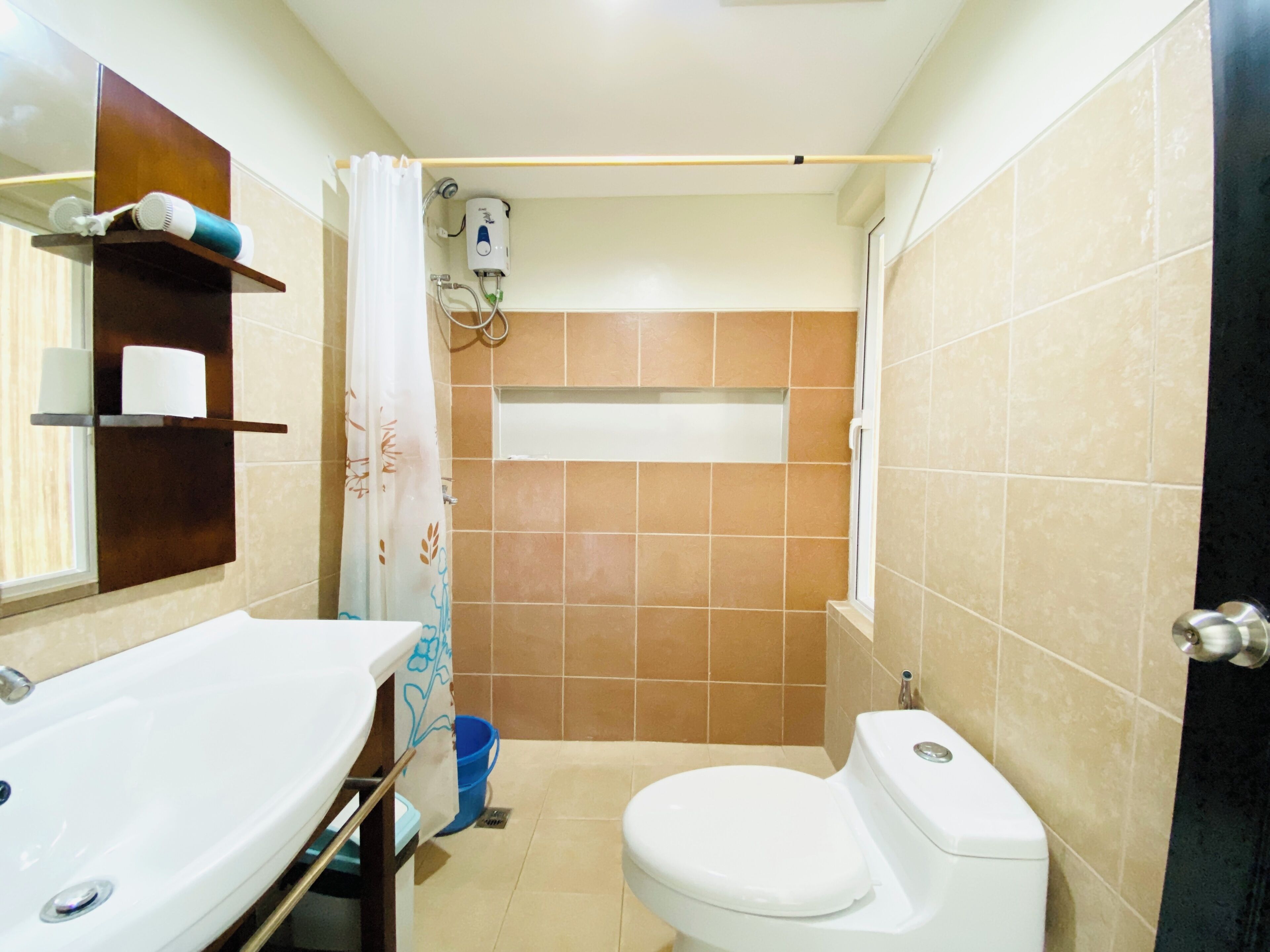 Un bany amb un lavabo blanc, un vàter, una zona de dutxa i un penjador de tovalloles.