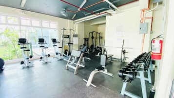 Un gimnàs amb diversos equips d'exercici, incloent esteves, aparells de musculació i pèses.