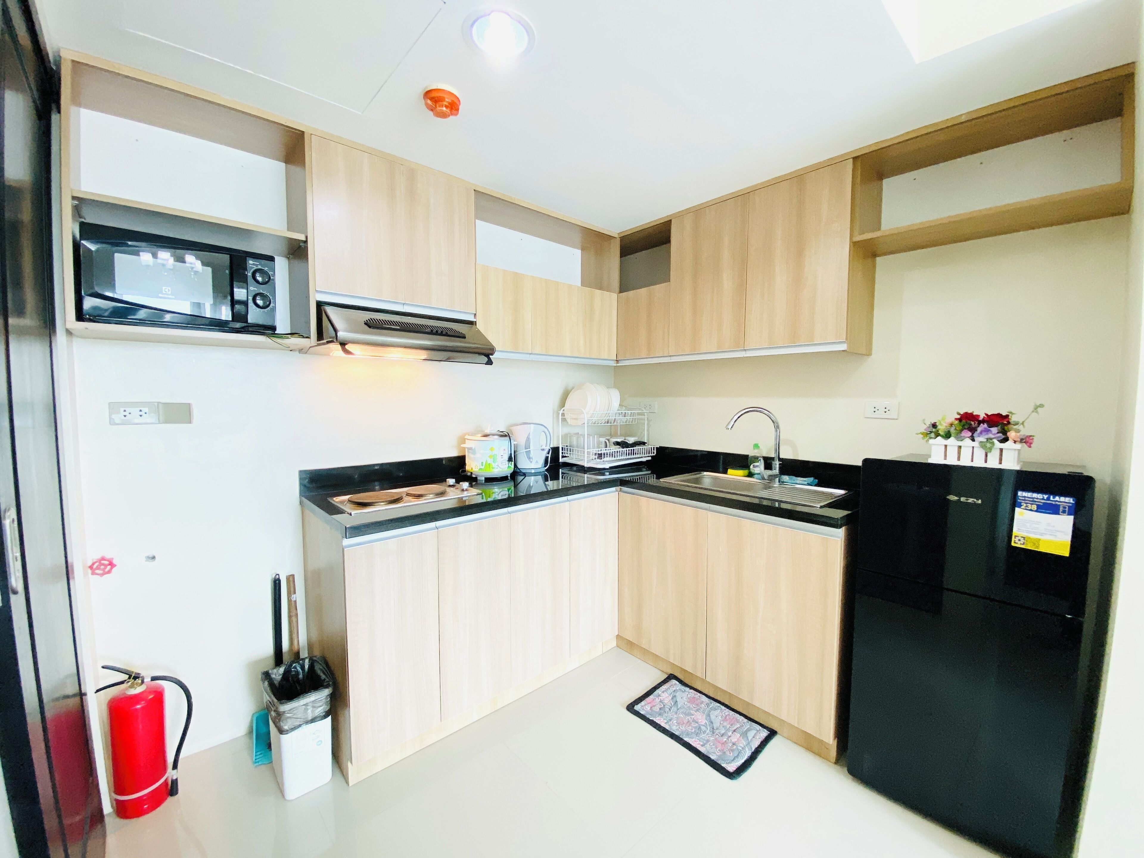 A compact kitchen with a microwave, toaster, sink, and black refrigerator.