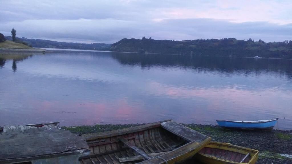 A calm lake with boats on the shore.