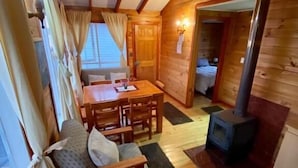 Un accogliente interno di una baita con arredamento in legno, una zona pranzo e un camino.