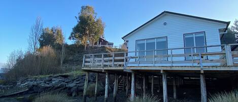 A house with a wooden deck and a rocky shoreline.