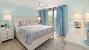 A bedroom with a bed, nightstands, a ceiling fan, and a window with curtains.
