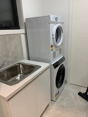 Ein kleiner Waschbereich mit Waschmaschine und Spüle.