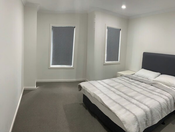 A bedroom with a bed, two windows, and a headboard.