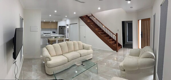 A modern living room with a sofa, a glass coffee table, and a TV.