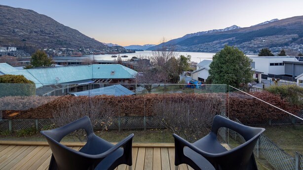 Una terraza con tres sillas que da a un lago y montañas.