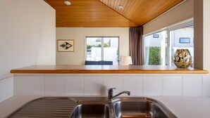 Una cocina con techo de madera, una ventana con vistas a la vegetación y un lavabo con grifo moderno.