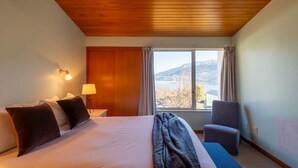 Habitación de hotel con una cama grande, un escritorio, una silla y una ventana con vistas a la montaña.