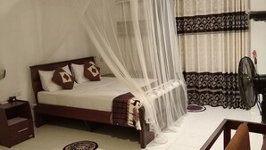 A bedroom with a bed under a mosquito net, a bedside table, a nightstand, a fan, and patterned curtains. - solitary resort  (Ella)