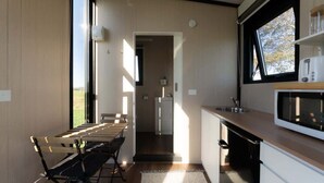 Una cocina moderna con comedor, vistas a través de una ventana y una encimera con microondas.