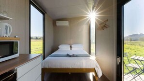 Un dormitorio con cama, televisor y vistas al exterior.