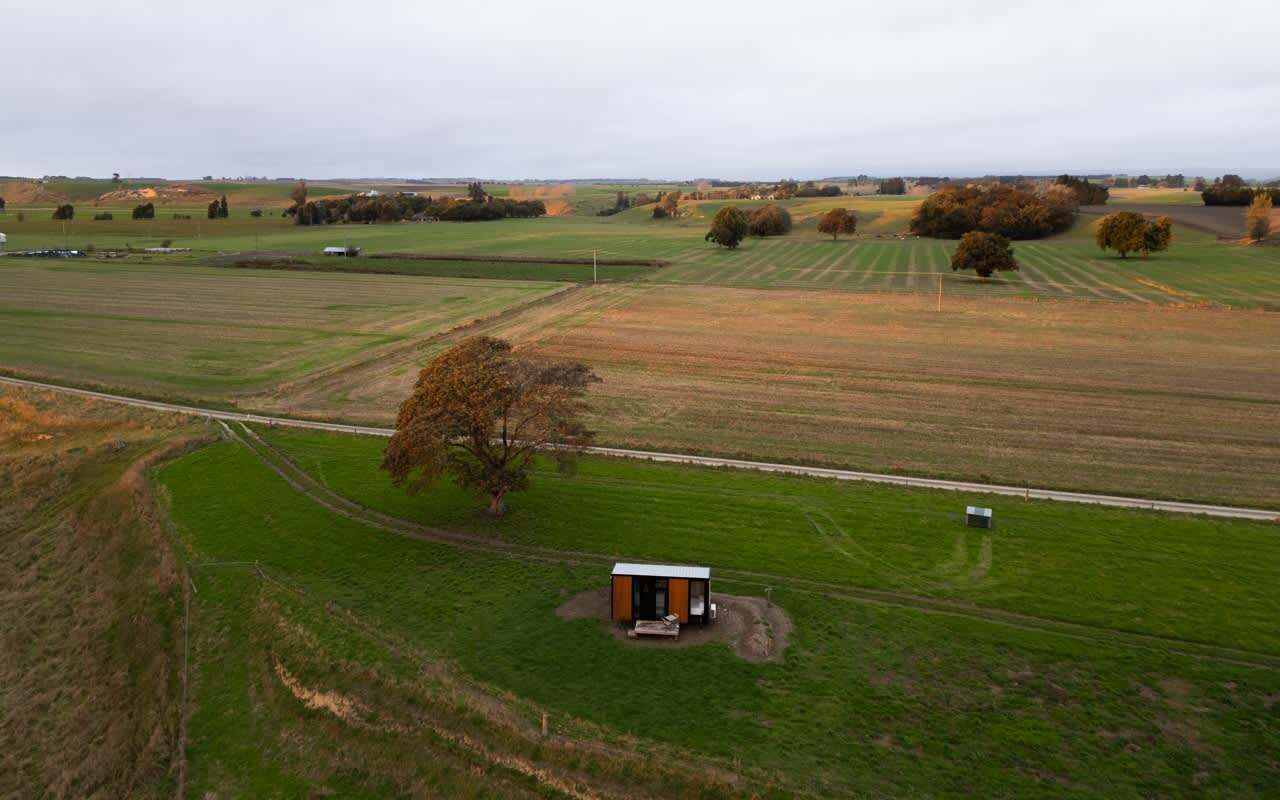 An aerial view of a rural landscape with fields, a small building, and a road.