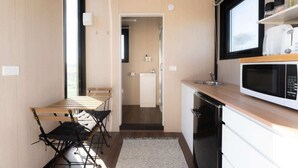 A compact kitchen with a microwave, sink, and a dining area with a table and chairs.