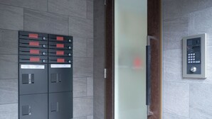 A modern elevator with a control panel and a set of lockers with red handles. - MATSUMIZAKA HILL by Tranova (Tokyo)