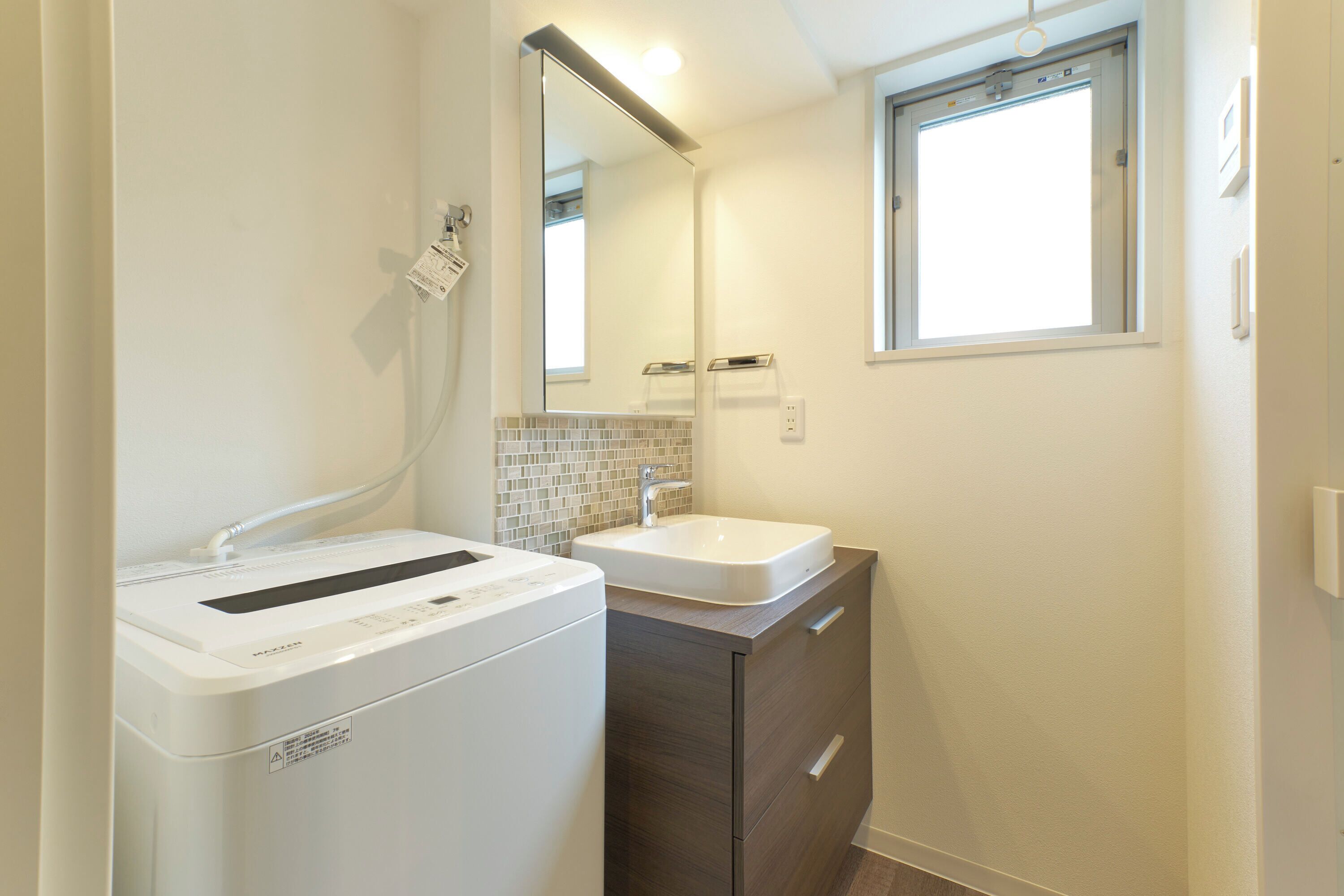 Ein modernes Badezimmer mit Waschmaschine, Waschbecken und Spiegel.
