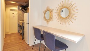 A modern kitchen with a white countertop, two chairs, and two wall-mounted mirrors. - MATSUMIZAKA HILL by Tranova (Tokyo)