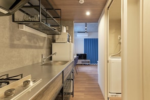 A modern kitchen with a stainless steel countertop, a built-in oven, and a microwave. - MATSUMIZAKA HILL by Tranova (Tokyo)