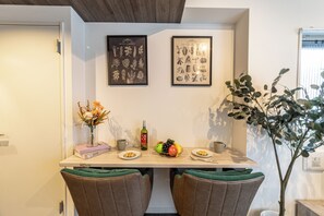 A dining area with a table set for two, a vase of flowers, a bottle of wine, and a fruit bowl. - MATSUMIZAKA HILL by Tranova (Tokyo)