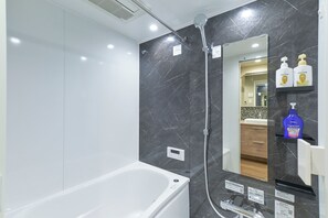 A modern bathroom with a bathtub, a shower, and a vanity with a mirror. - MATSUMIZAKA HILL by Tranova (Tokyo)