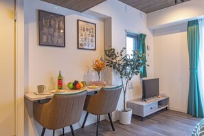 A dining area with a table, chairs, a potted plant, a bottle, and a television. - MATSUMIZAKA HILL by Tranova (Tokyo)