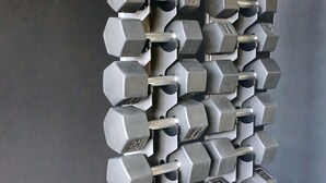 A wall-mounted dumbbell rack with multiple pairs of adjustable dumbbells.