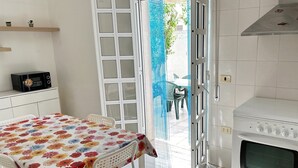 A kitchen with a microwave, a table with a floral tablecloth, and an oven. - Villetta Zagara | outdoor space, a/c, 2 bedrooms (Porto Cesareo)