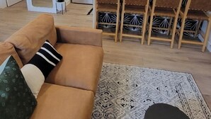 Uma sala de estar moderna com um sofá, um tapete estampado e uma área de jantar com um balcão.