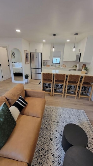 Un salon moderne avec un canapé, un tapis à motifs et un coin repas doté d’un bar.