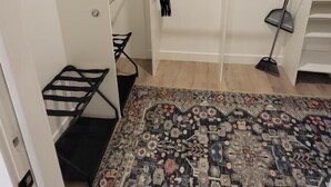 Um closet espaçoso com prateleiras abertas, cabideiro e um tapete estampado no chão.