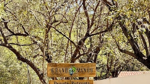 Un letrero de madera que anuncia diversos servicios, incluyendo retiros privados, restaurante con productos de la granja, hotel boutique y una reserva comunitaria.
