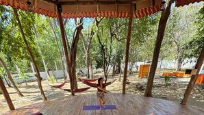 Una terraza de madera con gente acostada sobre esterillas, en una posición relajada, posiblemente para una sesión de yoga o estiramientos.