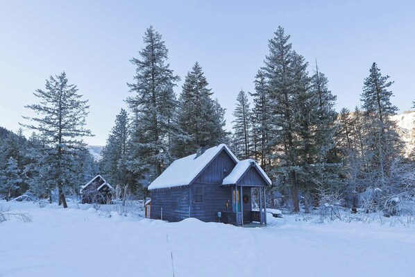 A wooden cabin surrounded by snow-covered trees.