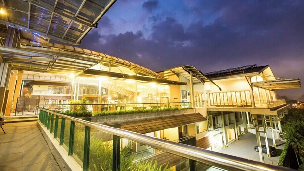 A modern building with a glass facade, outdoor seating, and a balcony. - Hotel Cianjur Cipanas (Cipanas)