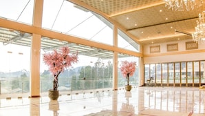 A spacious lobby with large windows, a polished floor, and two large vases with pink flowers. - Hotel Cianjur Cipanas (Cipanas)