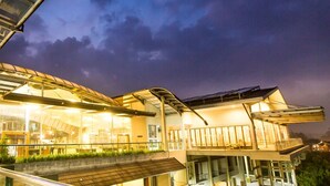 A modern building with a glass facade, a flat roof, and a balcony area. - Hotel Cianjur Cipanas (Cipanas)