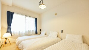 A hotel room with two beds, a bedside lamp, a window with curtains, and a ceiling light. - Fine court Yamahana (Sapporo)